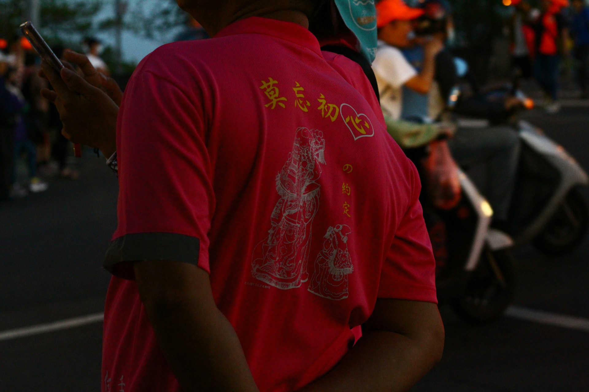 A man in a red shirt looking at his cell phone